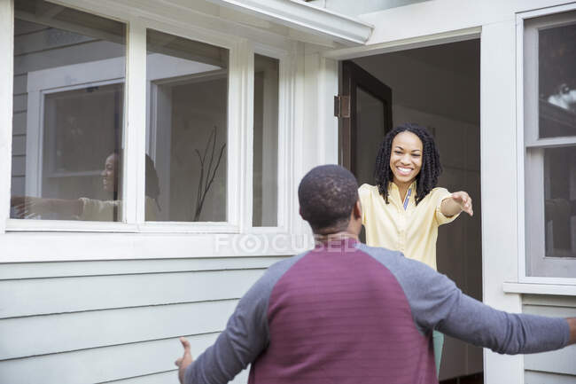 Enthusiastic woman greeting man in doorway — Stock Photo