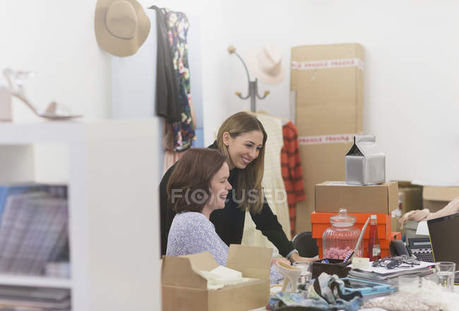 Fashion buyers working at laptop in messy office — Stock Photo