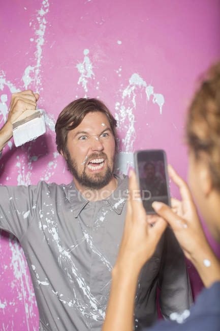Woman taking picture with cell phone of man with paintbrush — Stock Photo