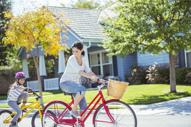 Mother and daughter riding bikes in street — Stock Photo