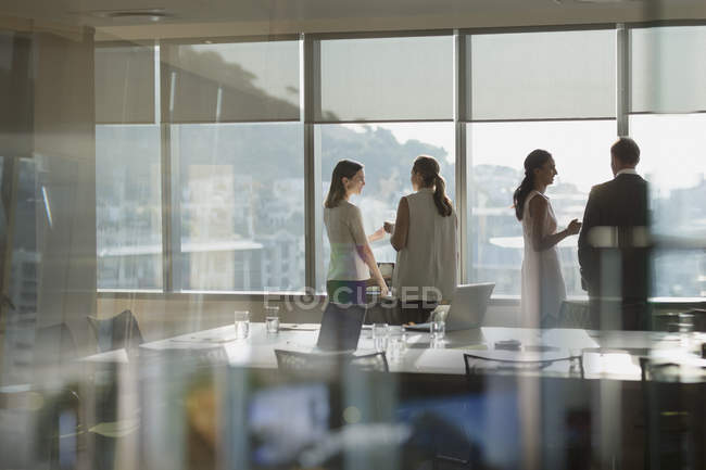 Деловые люди разговаривают за солнечным окном в конференц-зале — стоковое фото