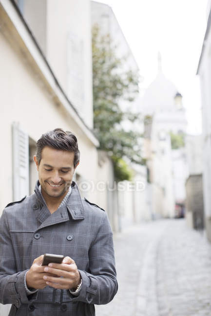 Businessman using cell phone on city street near Sacre Coeur Basilica, Paris, France — Stock Photo