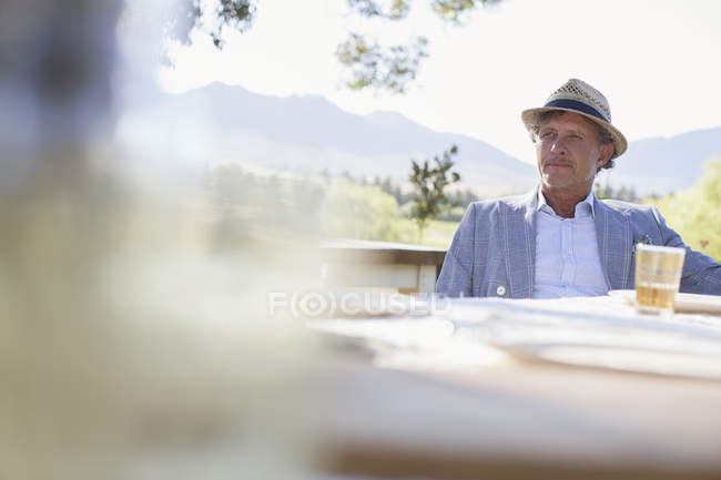 Homme plus âgé assis à la table à manger extérieure — Photo de stock