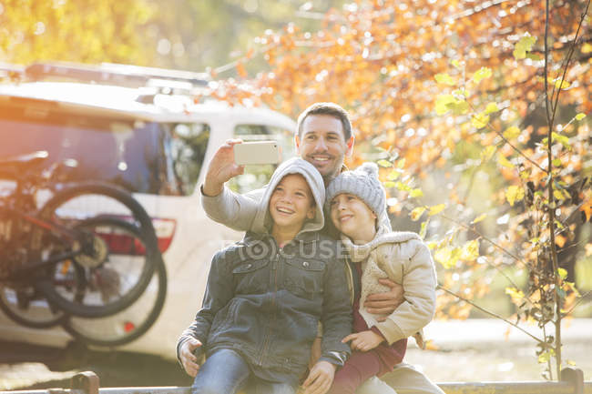 Padre e hijos tomando selfie en el parque de otoño - foto de stock