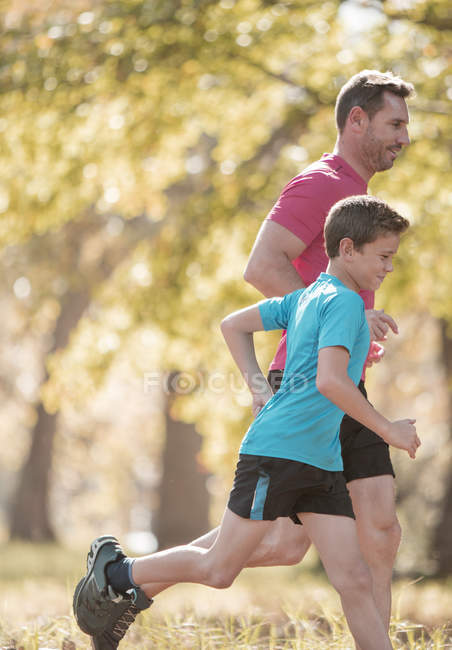 Father and son jogging in park together — Stock Photo