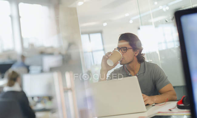 Творчі бізнесмен питної кави, працює на ноутбуці в офісі — стокове фото