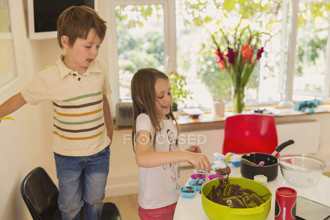 Boy and girl brother and sister making chocolate cupcakes in kitchen — Stock Photo