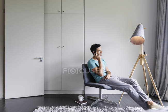 Uomo che parla al cellulare in salotto — Foto stock