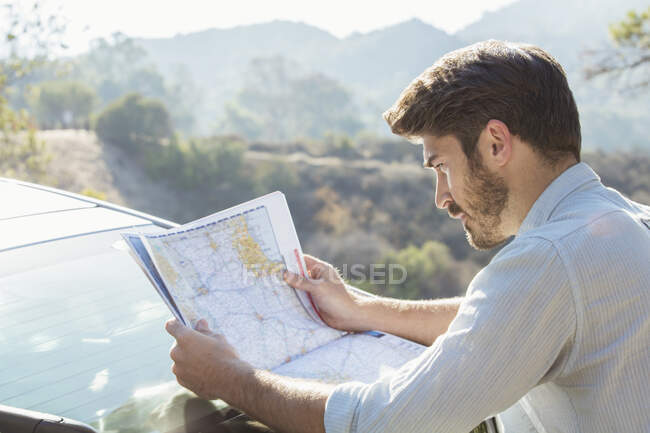 Man looking at map outside car — Stock Photo
