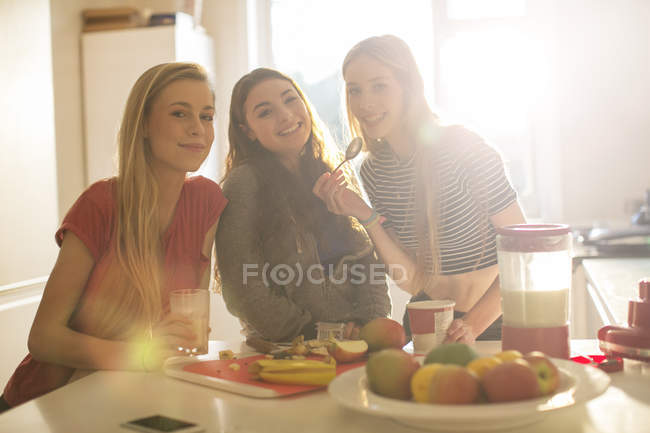 Portrait teenage girls eating in sunny kitchen — Stock Photo