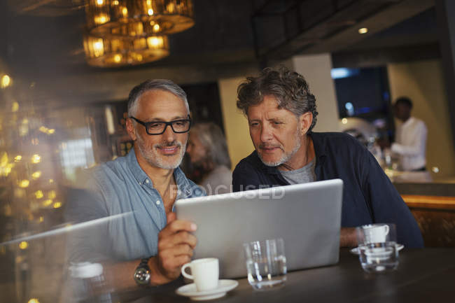 Men using laptop at restaurant — Stock Photo