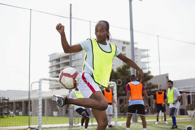 Jogador de futebol executando truque com futebol no campo — Fotografia de Stock