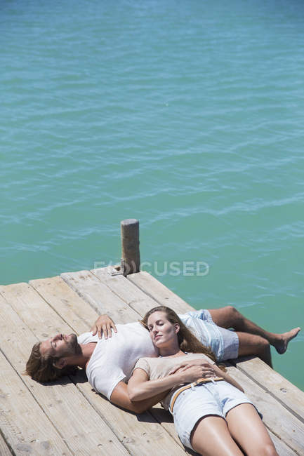 Couple relaxing together on wooden dock — Stock Photo
