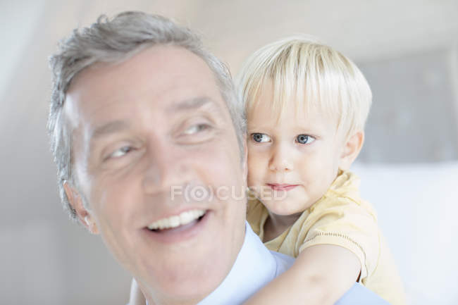 Отец, несущий маленького сына на спине — стоковое фото