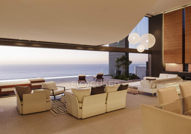 Salon dans maison moderne avec vue sur l'océan au coucher du soleil — Photo de stock