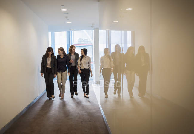 Businesswomen walking in a row in office corridor — Stock Photo