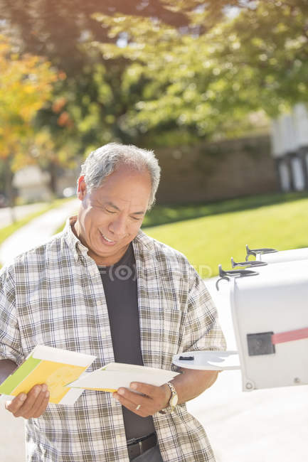 Человек забирает почту у почтового ящика — стоковое фото