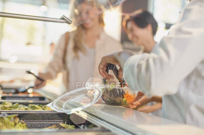 Young women serving salad at salad bar in grocery store market — Stock Photo