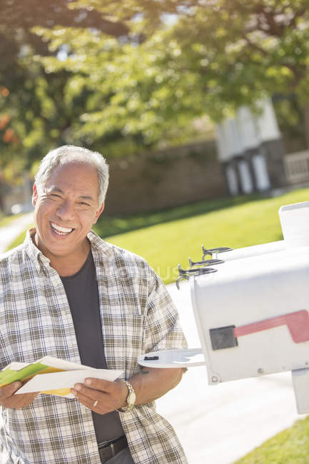 Портрет улыбающегося человека, забирающего почту из почтового ящика — стоковое фото