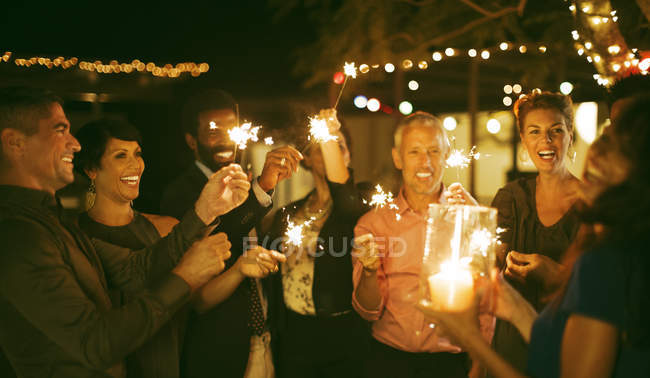 Друзья играют со сверкающими на вечеринке — стоковое фото
