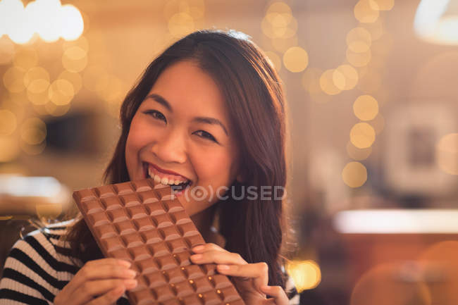 Portrait Chinese woman with sweet tooth craving biting into large chocolate bar — Stock Photo