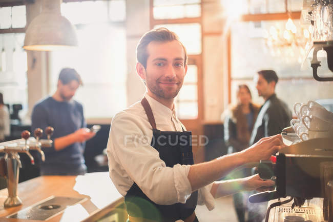 Портрет улыбающийся мужчина-бариста с помощью кофеварки в кафе — стоковое фото