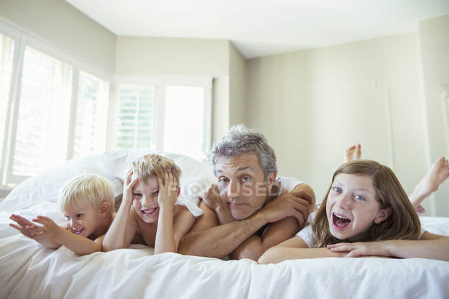 Padre e figli si rilassano sul letto — Foto stock