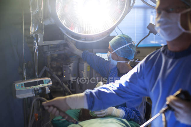 Cirujanos masculinos y femeninos que realizan cirugía laparoscópica en quirófano - foto de stock