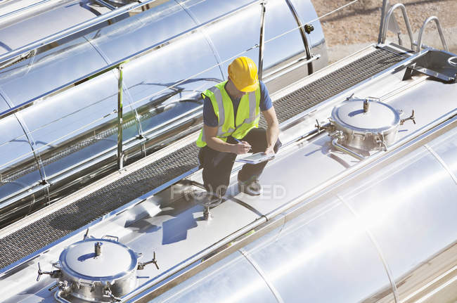 Worker using digital tablet on top of stainless steel milk tanker — Stock Photo