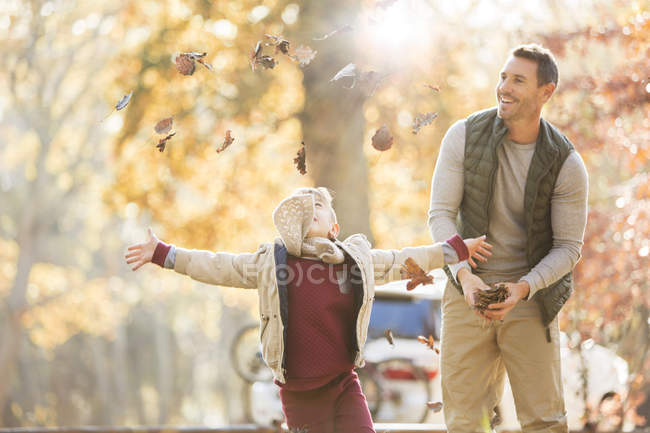 Padre e hijo lanzando hojas de otoño por encima - foto de stock