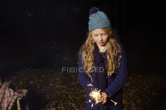 Девушка играет с игристым на открытом воздухе в ночное время — стоковое фото