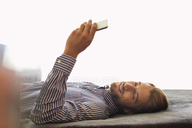 Junger attraktiver Mann benutzt Handy auf Bank — Stockfoto
