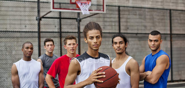 Мужчины стоят на баскетбольной площадке и смотрят в камеру — стоковое фото