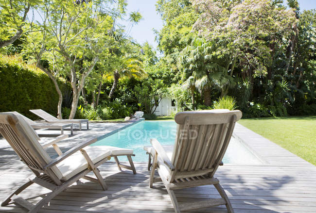 Lawn chairs and swimming pool in backyard — Stock Photo