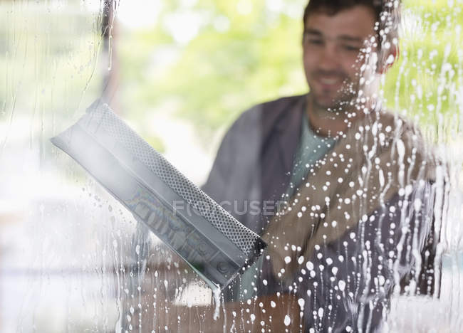 Geschickter Kaukasier wäscht Fenster mit Rakel — Stockfoto