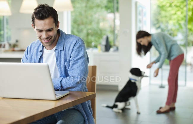 Man using laptop at kitchen table at modern home — Stock Photo