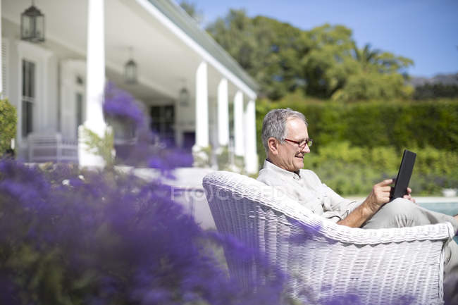 Старший білий чоловік використовує цифровий планшет в саду — стокове фото