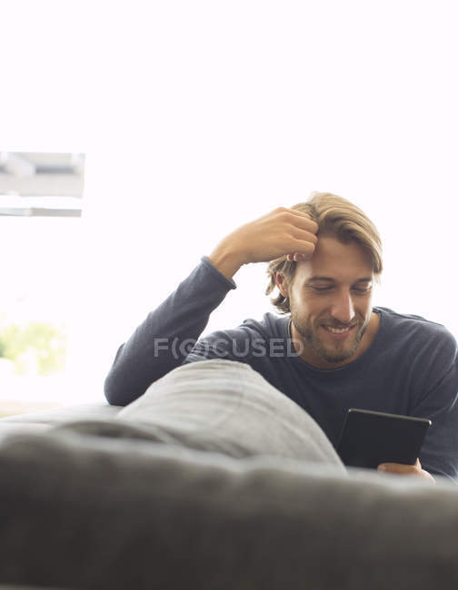 Hombre usando tableta ordenador en el sofá - foto de stock
