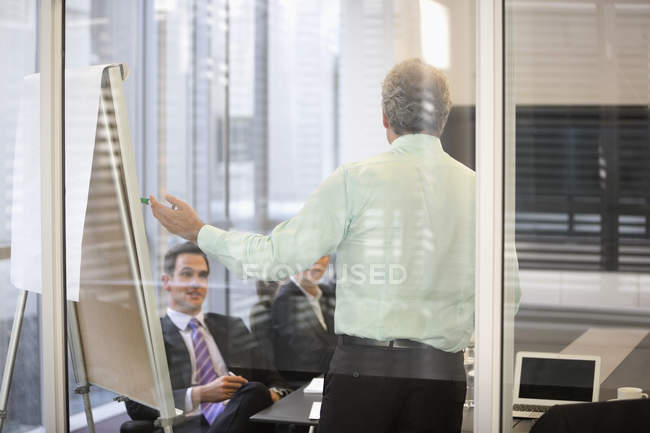 Homme d'affaires au tableau à feuilles mobiles en réunion au bureau moderne — Photo de stock
