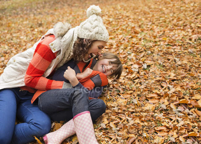 Mother and daughter playing in autumn leaves — Stock Photo