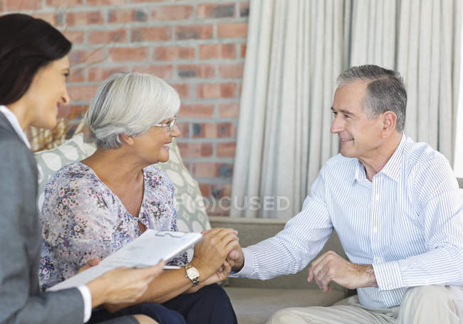 Conselheiro financeiro conversando com casal no sofá — Fotografia de Stock