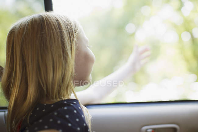 Girl reaching out of car window — Stock Photo