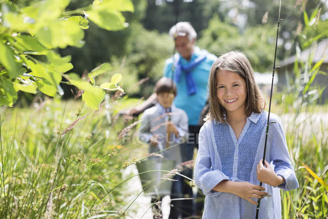 Girl carrying fishing rod in tall grass — Stock Photo