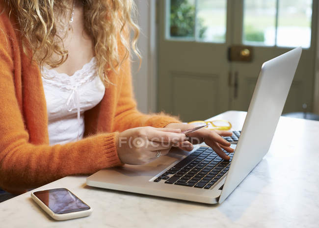 Frau kauft mit Laptop drinnen ein — Stockfoto