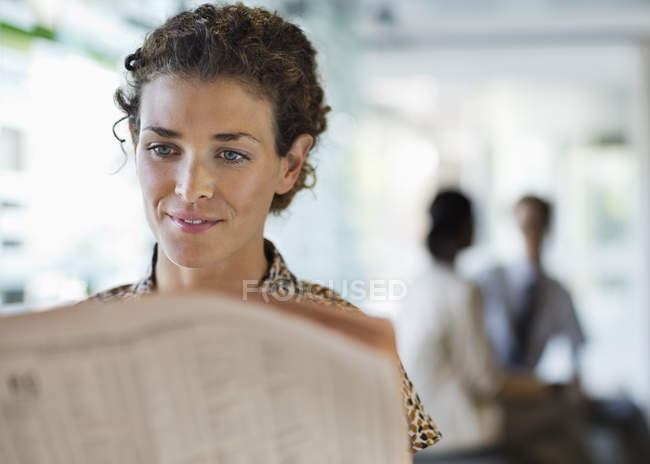Businesswoman reading newspaper at desk — Stock Photo