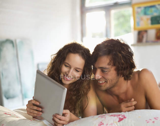 Молода пара використовує планшетний комп'ютер у ліжку — стокове фото