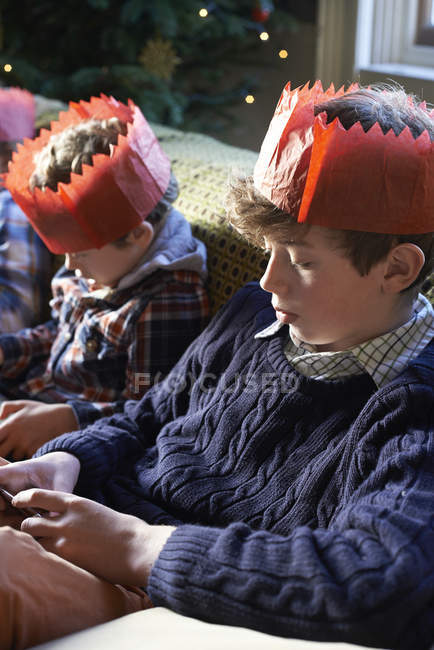 Children in paper crowns relaxing on sofa — Stock Photo