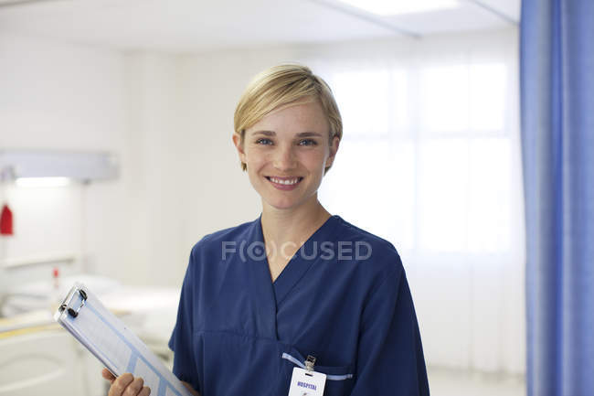 Enfermera sonriendo en la moderna habitación del hospital - foto de stock