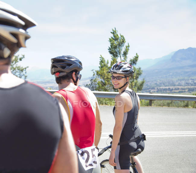 Ciclistas caucásicos adultos hablando en carretera rural - foto de stock