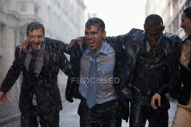 Uomini d'affari felici che camminano in strada piovosa — Foto stock